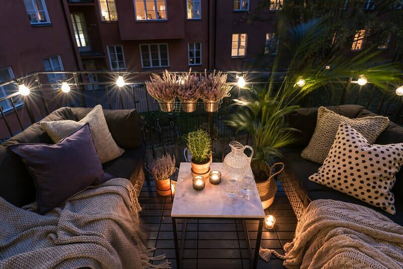 balcon avec des canapés et des guirlandes lumineuse